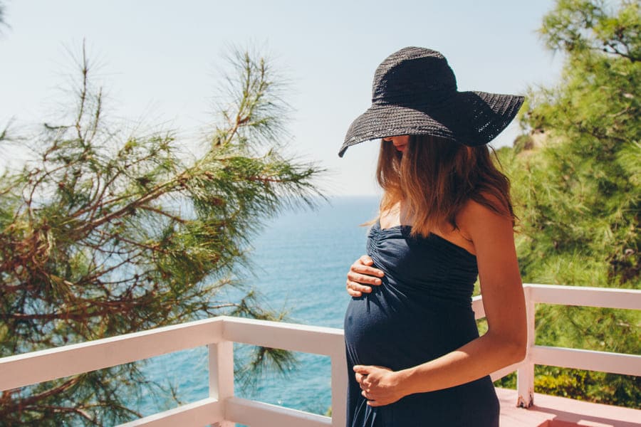 tourism leisure is beautiful pregnant girl with long hair basking black dress hat balcony hotel with views tropical plants small building (1) (1)